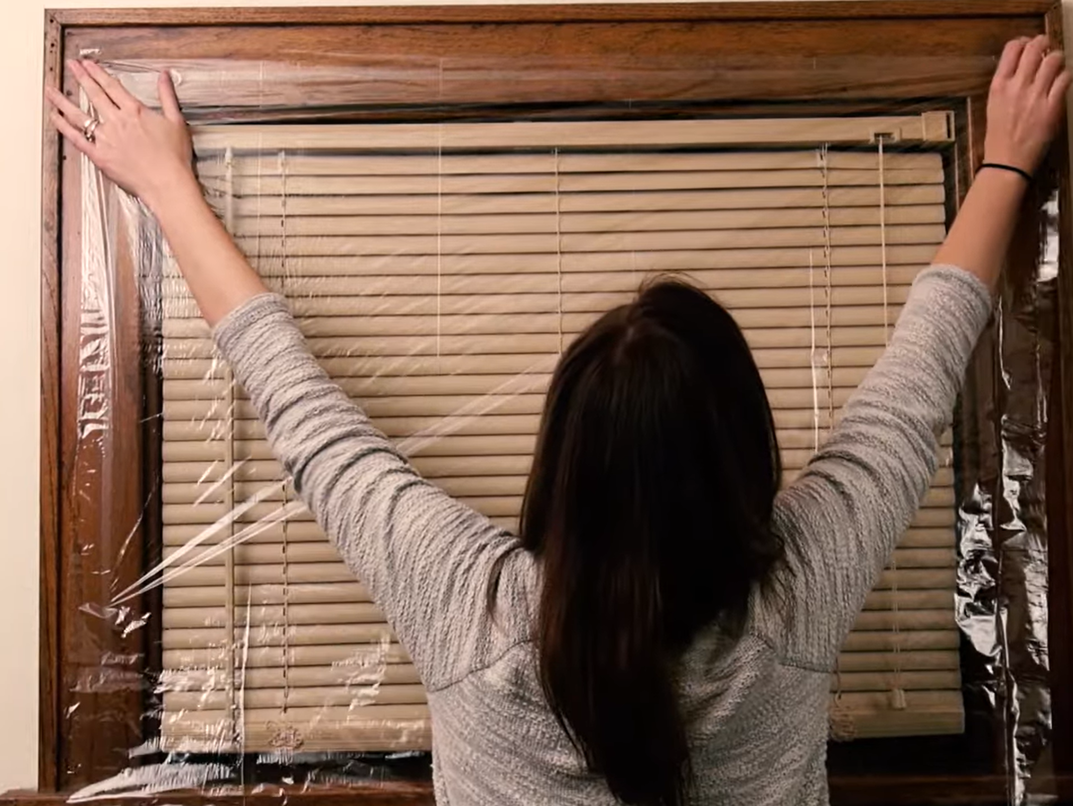 Woman applying shrink wrap film to a window